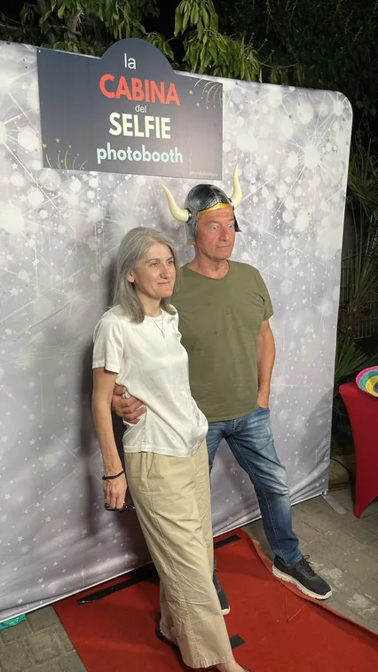 Di sera, davanti al fondale bianco a stelle con l'insegna «la Cabina del Selfie photobooth», due invitati posano in piedi su un tappeto rosso; lui indossa un elmo da vichingo con le corna.